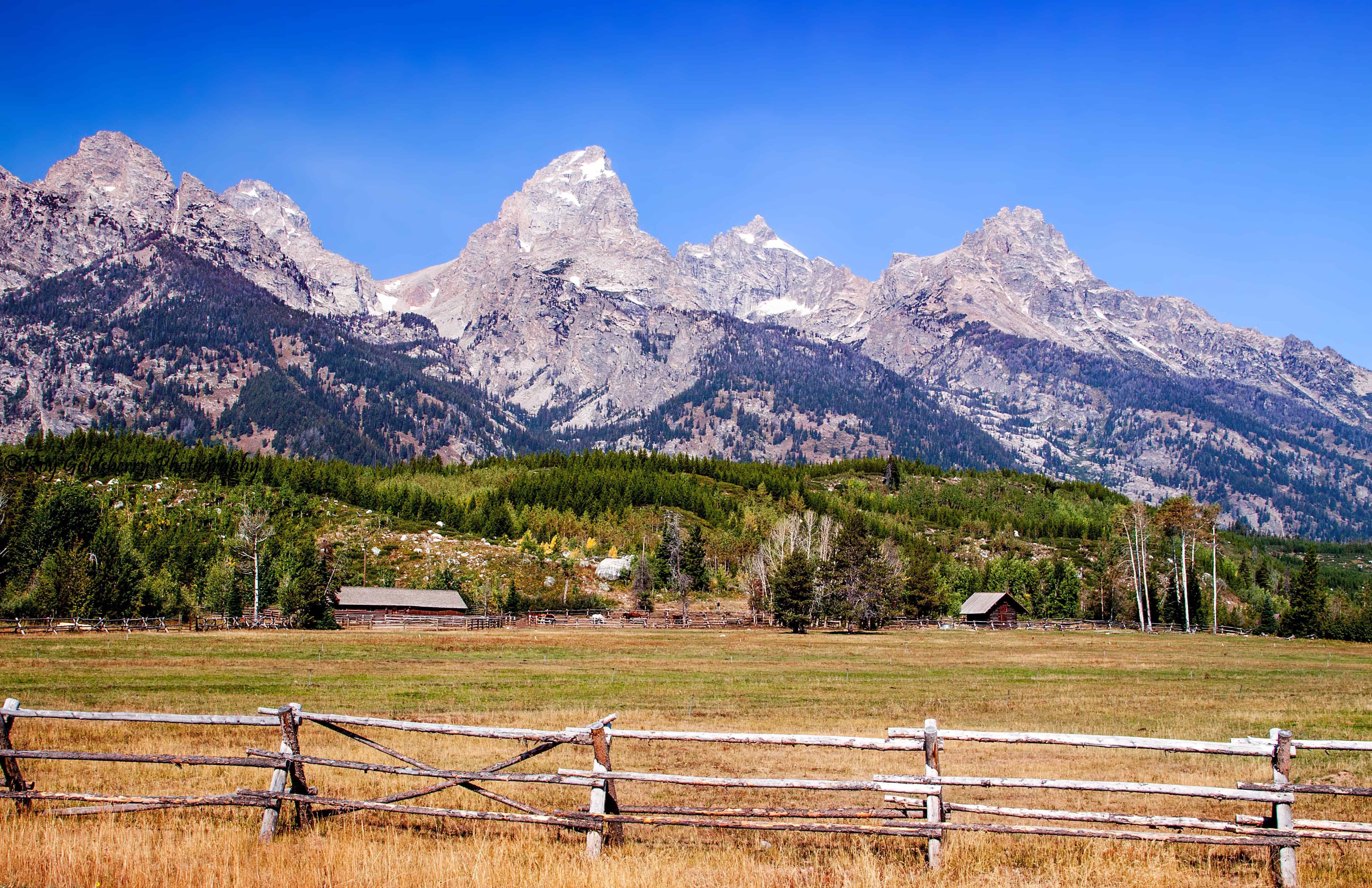 Grand Teton landscape with wooden fence and mountains.