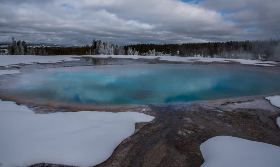 Views of hot pools against white snow when you visit Yellowstone in the winter.