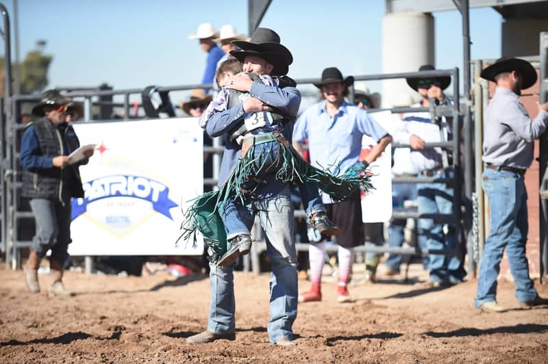 man and boy embrace at a rodeo